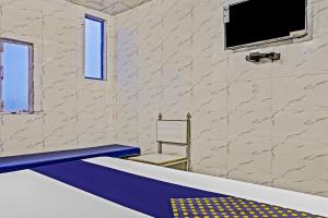 a bath tub with a chair and a television on a wall at Hotel O Sona in Bhopal