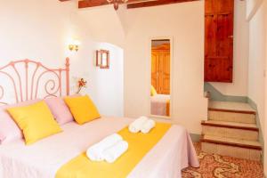 a bedroom with a bed with yellow and pink pillows at Casa Casanova in Benissa