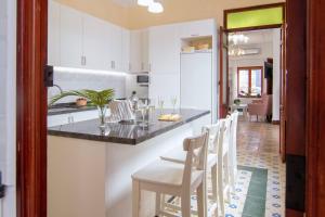 a kitchen with a bar with white cabinets and white chairs at Casa Casanova in Benissa