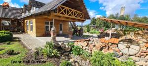 a small house with a stone wall in the yard at Vilimu Sodyba - Event Hall in Kriukai