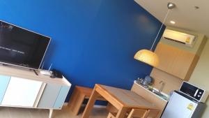 a room with a blue wall and a table and a desk at Baan Thew Talay Blue Sapphire in Cha Am