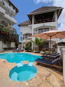 a swimming pool in front of a building with umbrellas at Boutique Ocean View Nungwi in Nungwi