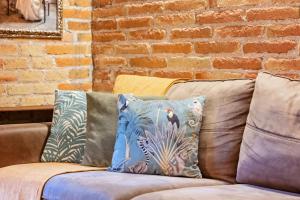 Un sofá con almohadas y una pared de ladrillos. en Sweett - Gallery Poble Sec, en Barcelona