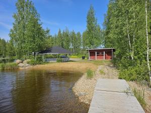 MaakeskiにあるRomantic countryside SAUNA Cottageの木製の橋がある川沿いの小屋