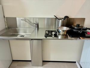a stainless steel kitchen counter with a sink and a stove at Corpo SKR by Tranova in Musashino
