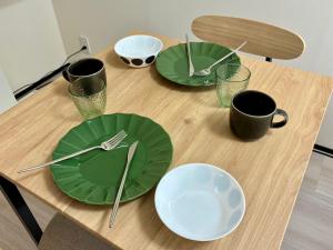 a table with green plates and utensils on it at Corpo SKR by Tranova in Musashino