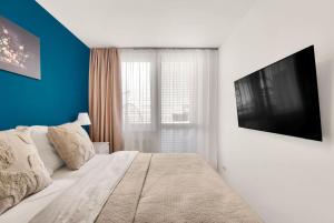 une chambre avec un lit avec une télévision sur un mur dans l'établissement Sky View Family Apartment, à Trnávka