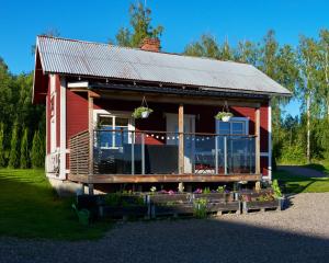 博伦厄Backes Lillstuga的一栋带阳台的红房子,前面有鲜花