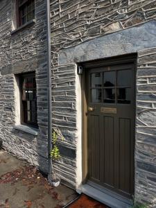 een gebouw met een deur en twee ramen bij Poets Cottage Eglwys Fach in Eglwys-fach