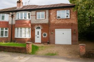 a brick house with two white garage doors at Hilton House - stylish 4-bed with parking in Manchester