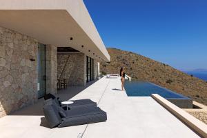 a woman standing next to a house with a swimming pool at Celestia Cove, Earthy Architecture Meets Endless Blue by etouri 