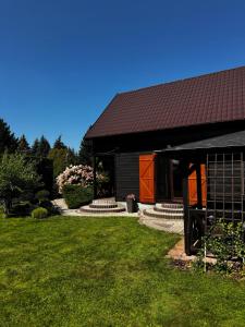 a house with a black roof and a grass yard at Malinowa na polu in Skorka