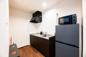 a small kitchen with a refrigerator and a microwave at Irodori Hotel HOTARU in Fukuoka