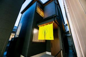 a door to a building with a yellow sign on it at Irodori Hotel HOTARU in Fukuoka