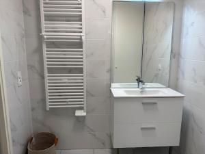 une salle de bain blanche avec un lavabo et un miroir dans l'établissement Laplace - 5 min from Paris and Parking, à Arcueil 10 autres photos