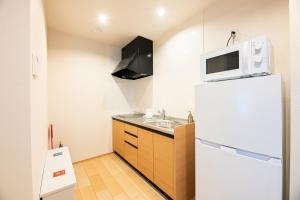 a small kitchen with a microwave on top of a refrigerator at Irodori Hotel KAZE in Fukuoka