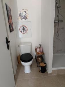 a bathroom with a toilet with a black lid at La Dune Bohème chic in Saint-Maurice-de-Beynost