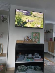 a television hanging on a wall above a shelf at La Dune Bohème chic in Saint-Maurice-de-Beynost