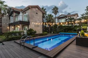 a house with a swimming pool in front of a house at Monaco Pool Pension in Seogwipo