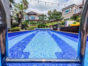 a pool with blue water in a house at Monaco Pool Pension in Seogwipo