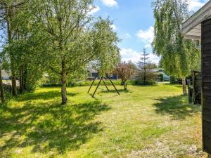 a yard with a swing set in the grass at Holiday Home Gerwin - 3km from the sea by Interhome in Blokhus