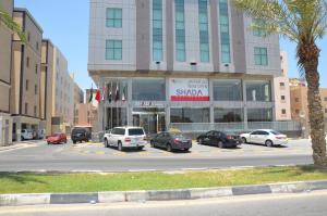 a street with cars parked in front of a building at Shada Residence Hotel in Al Khobar