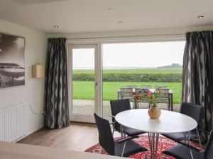 een eetkamer met een tafel en stoelen en een groot raam bij Holiday Home Spase - 250m to the fjord by Interhome in Nakskov