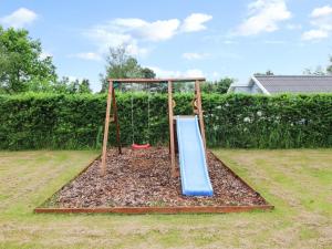 a playground with a slide in a yard at Holiday Home Gretta - 400m from the sea by Interhome in Dannemare