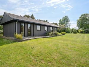a black house with a large grass yard at Holiday Home Veljan - 400m from the sea by Interhome in Bogense