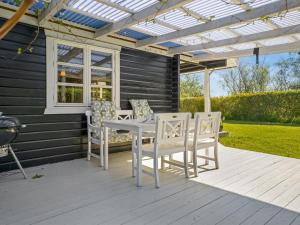 a white table and chairs on a porch with a pergola at Holiday Home Lamberthus - 600m from the sea by Interhome in Rødby +17 photos