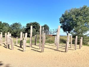 Una valla de madera en la arena con un puente al fondo. en Holiday Home Ulv - 25m from the sea by Interhome, en Otterup