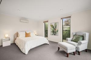 ein weißes Schlafzimmer mit einem Bett und einem Stuhl in der Unterkunft Malabar Retreat by Ready Set Stay in Cowes + 11 Fotos