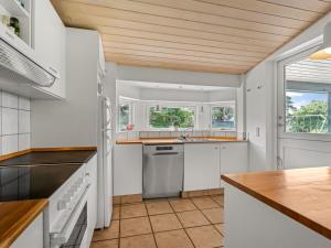a kitchen with white cabinets and a wooden ceiling at Holiday Home Allie - 150m from the sea by Interhome in Rødby