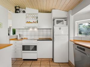 a kitchen with white appliances and white cabinets at Holiday Home Allie - 150m from the sea by Interhome in Rødby