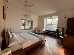 Un dormitorio con una cama y un escritorio y dos ventanas. en Sandyview-Private Villa On The Beach, en Chennai