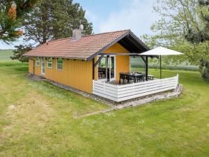 a small yellow house with a table and an umbrella at Holiday Home Janne - 400m from the sea by Interhome in Bogense