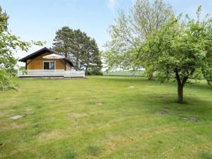 a small yellow house in a field with a tree at Holiday Home Janne - 400m from the sea by Interhome in Bogense