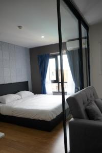 Ban Pra DokにあるCondo Caesar's Suite Koratのベッドとソファと窓のある寝室