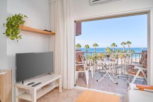 a living room with a tv and a balcony with the ocean at Apartamento Gondolas Costa Tropical in Almuñécar