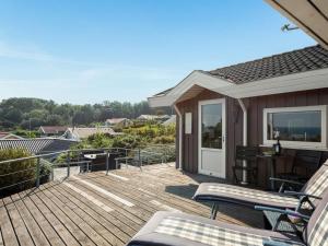 eine Holzterrasse mit einem Tisch und Stühlen darauf in der Unterkunft Holiday Home Ebbeline - 150m from the sea by Interhome in Binderup Strand