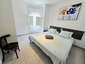 a bedroom with a bed and a chair and a window at Apartamentos Medano - Playa Grande in El Médano