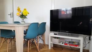 a dining room table with a television and blue chairs at Apartament VINCENT in Mrągowo