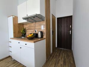a kitchen with white cabinets and a wooden door at Place4You Studio w Sercu Ostródy in Ostróda