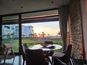 a dining room with a table and chairs and a large window at Beach Front Luxury Apartment Sidi Rahal in Sidi Rahal