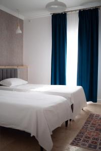 two beds in a bedroom with blue curtains at Complex Chitu, Odihna, Camere Cozy si Cazino in Izbiceni