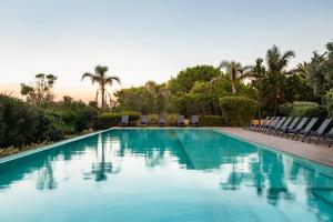 uma piscina com cadeiras e palmeiras em Eurostars Cascais em Cascais