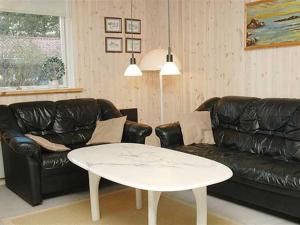 a living room with a black leather couch and a white table at Holiday Home Jarmunrek - 1km from the sea by Interhome in Hejls
