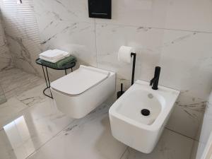 a white bathroom with a toilet and a sink at Sui Generis Montesilvano Colle in Montesilvano +17 photos
