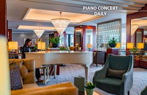 a woman sitting at a piano in a hotel lobby at Grand Hotel Prague Towers - Czech Leading Hotels in Prague