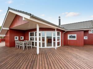 a house with a wooden deck with a table at Holiday Home Henrijette - 200m from the sea by Interhome in Sjølund